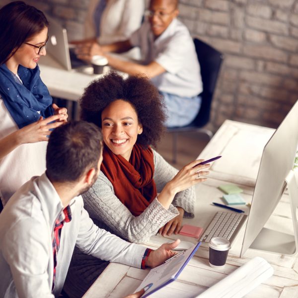 Group of young employees in office talking and working